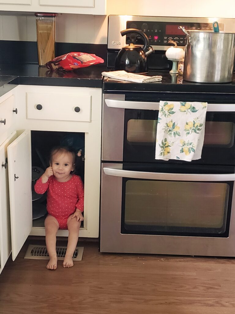 a little girl sitting in the cabinet, stay at home mom life
