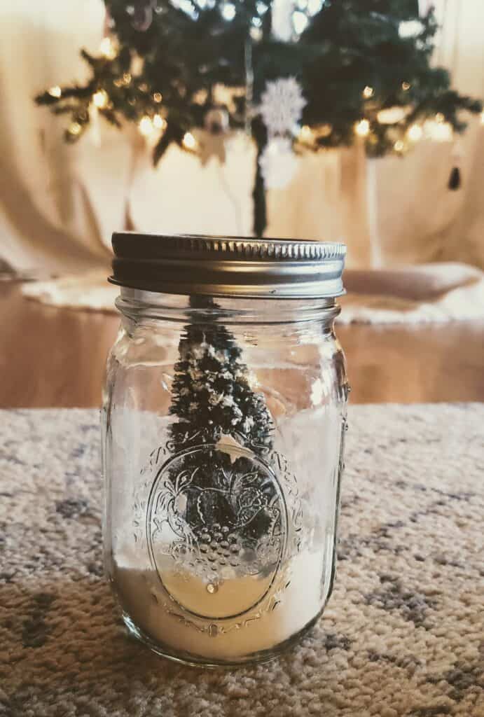 a Christmas tree in a snow filled mason jar in front of a big Christmas tree, should Christians have Christmas trees? Should Christians celebrate Christmas?