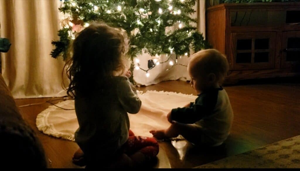 a little boy and a little girl sitting beneath a Christmas tree